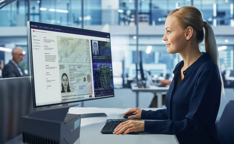 woman sitting at desk using a scanner to verirfy an ID document, with the document shown on screen.